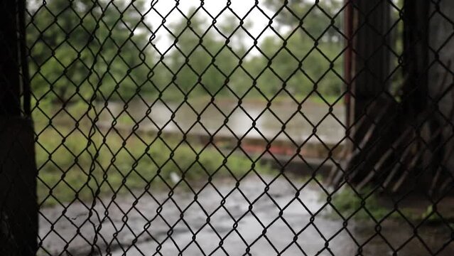 toma detalle de un alambrado metalico en ambiente abandonado con clima lluvioso, video HD