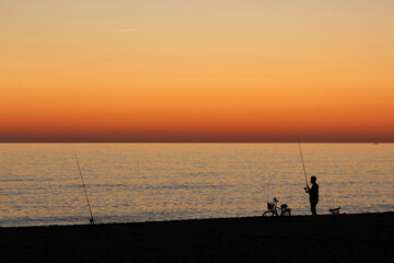 a fisherman at sunset catching fish in the sea