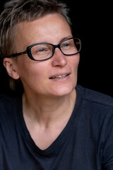 Fototapeta premium Portrait of caucasian woman with short haircut and black-rimmed glasses on black background, close-up. Emotions on face. High quality photo