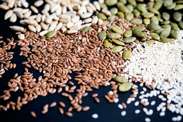 Various seed on the black. Flax, sesame, sunflower and pumpkin seed, close up.