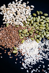 Various seed on the black. Flax, sesame, sunflower and pumpkin seed, close up.
