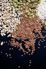 Various seed on the black. Flax, sesame, sunflower and pumpkin seed, close up.