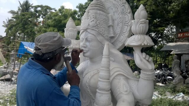 Indian craftsman carving traditional Hindu Goddess Lakshmi or Laxmi White marble stone Sculpture or statue For Sale, Using Hammer And Chisel, hand moving.