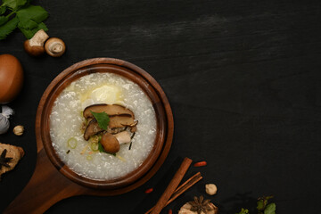 Delicious rice porridge with soft boiled egg, shiitake mushroom, slice ginger and scallion in wooden bowl. Top view with copy space