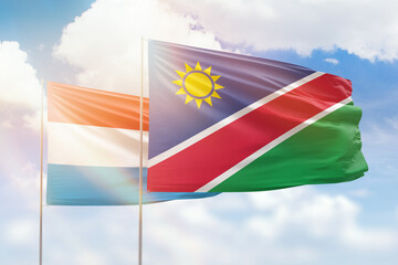 Sunny blue sky and flags of namibia and luxembourg