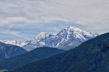 Fototapeta na wymiar Blick vom Reschenpass auf ein Bergmassiv mit schneebedeckten Gipfeln und Wäldern im Vordergrund