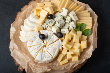 Cheese assortment on  plate with red wine on  a dark background. Copy space.