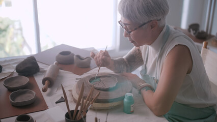 Asian elderly woman enjoying pottery work at home. A female ceramicist is making new pottery in a studio.