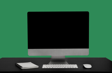 Stylish workspace with blank screen desktop computer at  Sea green background.