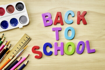 the phrase back to school is laid out in multicolored letters on the table a fountain pen a paint brush a ruler next to the concept of education school