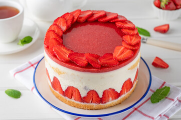 Fraisier mousse cake. Strawberry cake with biscuit, mousse and jelly on a white wooden background. Summer dessert. Selective focus. Copy space.