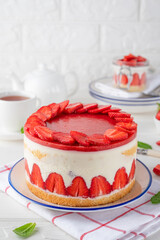 Fraisier mousse cake. Strawberry cake with biscuit, mousse and jelly on a white wooden background. Summer dessert. Selective focus. Copy space.