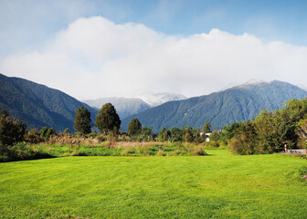 Fototapeta na wymiar natural scenery, meadows snow covered mountains white cloundy blue sky, New Zealand