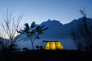 Fototapeta na wymiar Camp and tent in the night in front of the mountains with cloud in natural park, Tourism concept