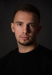 Fototapeta premium portrait of handsome man sitting on chair in dark studio 