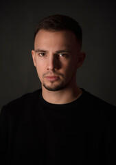 portrait of handsome man sitting on chair in dark studio  