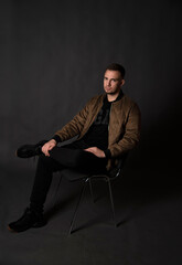 portrait of handsome man sitting on chair in dark studio  