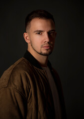 portrait of handsome man sitting on chair in dark studio  