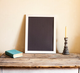 vintage interior,stillife on the table against wall , book and candlestick and the frame for the photo or picture
