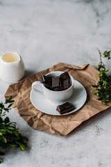 Cubes of cocoa mass in a white coffee cup milk jug espresso greens on a white background