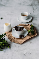 Cubes of cocoa mass in a white coffee cup milk jug espresso greens on a white background