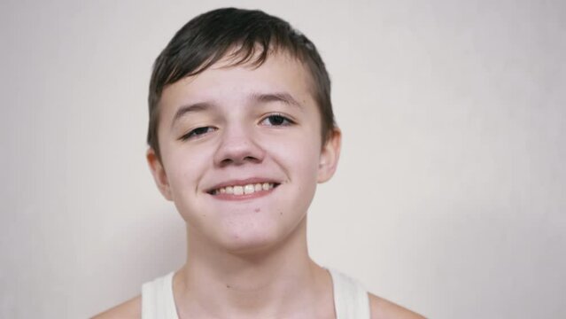 Smiling Teenager Gesticulates with Mouth, Showing his Teeth, Tongue. Smile. A handsome boy with a drooping eyelid, a wide smile looks at the camera, grimaces. Facial expressions of a positive child.
