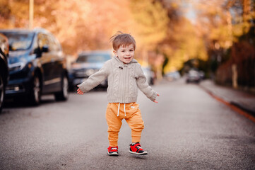 Fototapeta premium Little toddler boy walking down the street in spring-autumn outfit