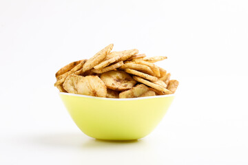 Salty banana chips in bowl on white background.