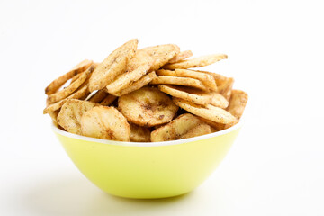 Salty banana chips in bowl on white background.