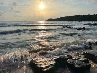 Sunset on the beach and ocean waves crashing against the rocks. orange sunset shadows.