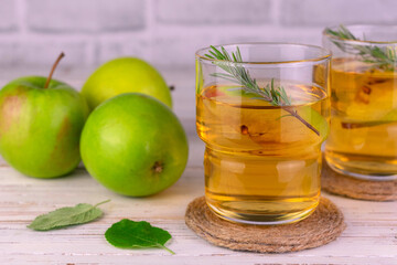 Two glasses of apple juice with a sprig of rosemary. Close-up.
