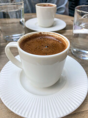 side view cup of Turkish coffee and water on table