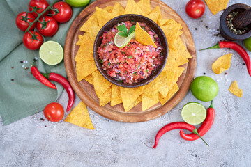 freshly made salsa dip sauce with nacho chips on wooden board