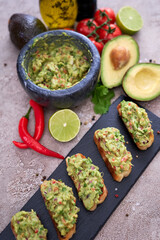 bruschetta with freshly made guacamole on grey concrete background