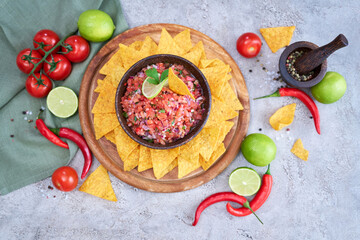 freshly made salsa dip sauce with nacho chips on wooden board