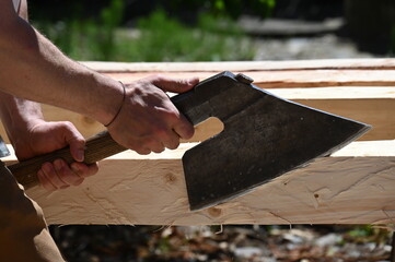 Bearbeitung eines Baumstammes mit dem Beil per Hand zur Herstellung eines Fachwerkbalkens
