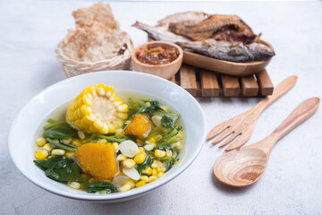 Selective focus of spinach clear soup with corn, sliced ​​garlic, pumpkin in a white bowl, in Indonesian it is called sayur bayam bening, Indonesian special food