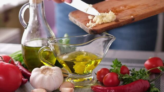 making garlic sauce - pouring crushed garlic into olive oil
