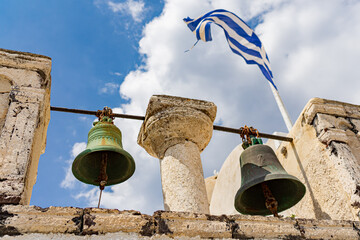 Two bells and the Greek flag on a bell tower in Oia on Santorini island