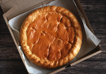 baked round cake with filling in a cardboard box for delivery