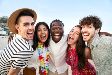 Portrait looking at camera of a five smiling friends enjoying the summer vacations. Group of people enjoying friendship on the beach. Young men and women of different races and nationalities.