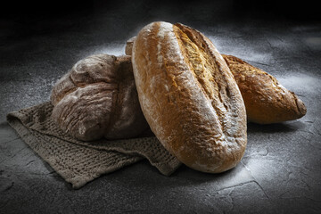 assortment of sourdough fresh breads on black background sprinkled with flour