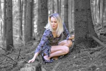 Carefree woman crouching on a forest floor in tattered dress