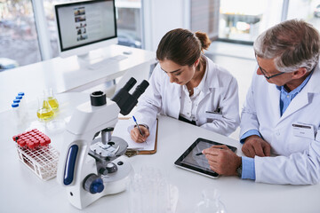 Making a full detailed analysis of their latest findings. Shot of two scientists having a discussion in a lab.