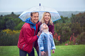 Rainy day adventures. Cropped portrait of a family of three standing outside in the rain.