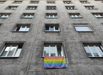 Pride month rainbow colored flag hanging from a window in the street