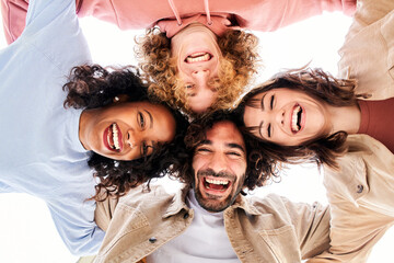 Circle of four happy young people looking at the camera embracing and having a fun. Smiling...
