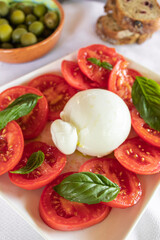 Red tomato salad with burrata cheese and fresh basil leaves Mediterranean style salad