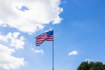 American flag waving in a blue cloudy sky. USA flag flies