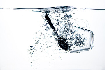 transparent glass dropped into the water on a white background